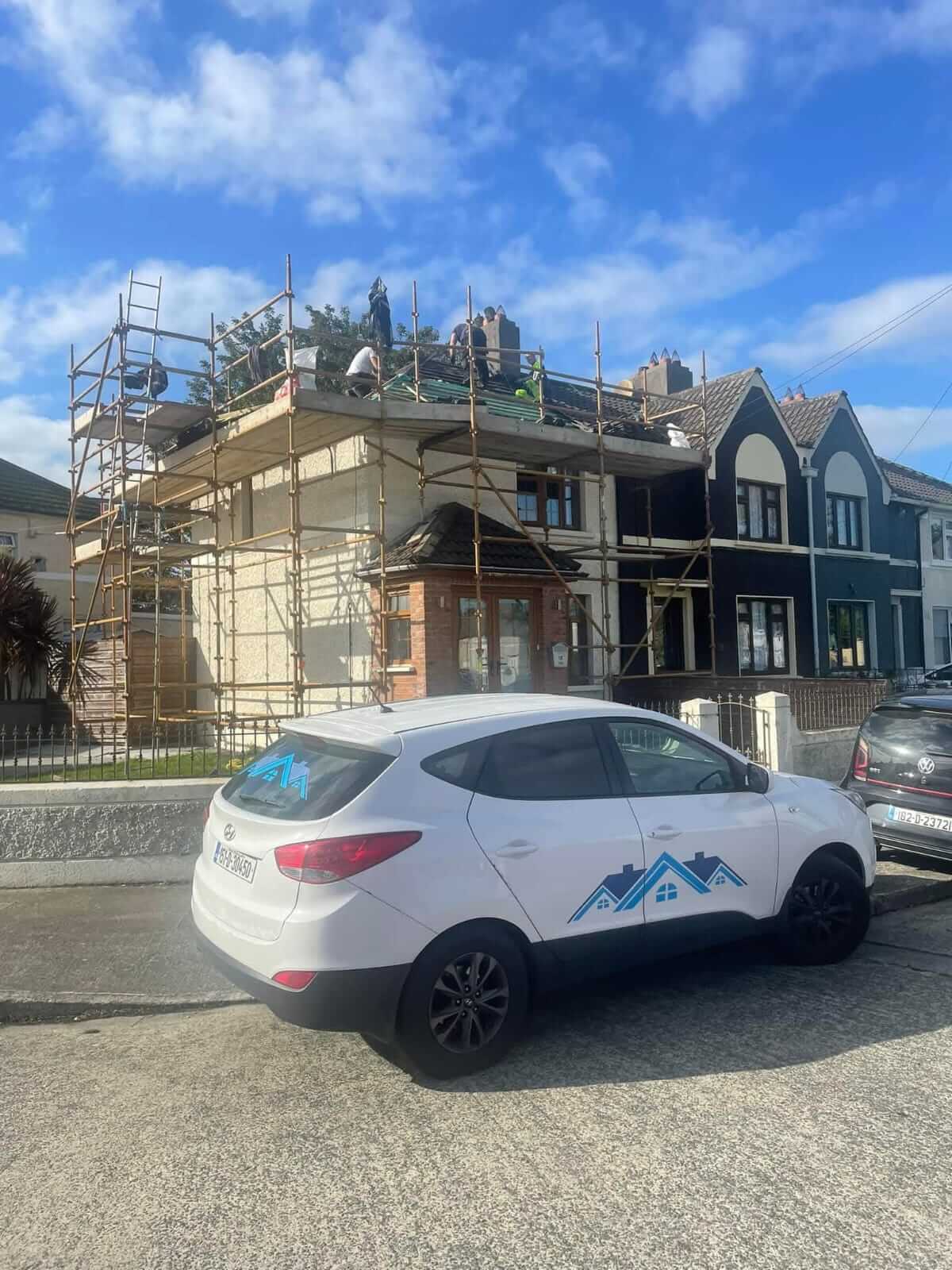 roofers fixing a roof with work car parked up outside house